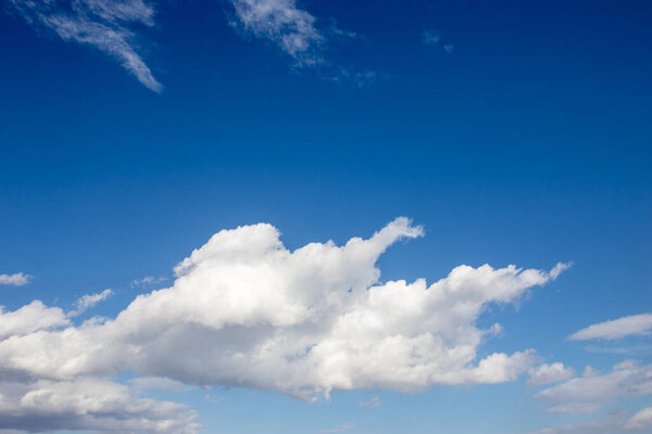 White fluffy clouds on bright blue sky on summer day