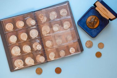 Numismatikler. Gümüş, altın ve bakırdan yapılmış eski ve pahalı koleksiyon paraları mavi arka planda şeffaf bir plastik albümde. 