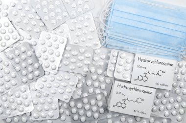 Hydroxychloroquine as possible a treatment for coronavirus. Tablets in boxes and blister with medical masks on white background. top view clipart