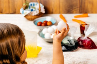 Paskalya yumurtalarını yemek boyasıyla ölmeye hazırlayan genç bir kız. Seçici odaklanma. Paskalya tatili