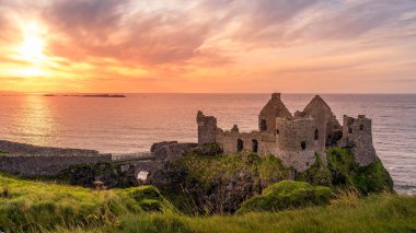 Bushmills uçurumundaki Dunluce Şatosu, gün batımı