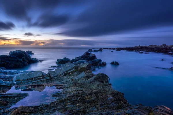 Crepúsculo começa a ceder à luz do dia na costa rochosa — Fotografia de Stock