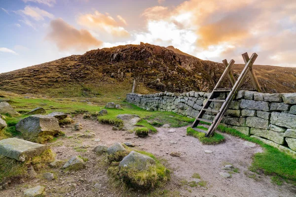 Pared de luto con escalera en la brecha de liebres que supervisa la montaña Slieve Bearnagh con puesta de sol — Foto de Stock