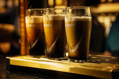 Selective focus on three pints of Guinness in glasses on bar or tap clipart