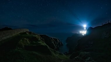 Fanad Head Deniz fenerinden parlayan ışık huzmeleri Yıldızlarla dolu karanlık bir gecede