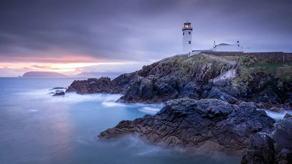 Twilight yields to dawn, sunrise at Fanad Head Lighthouse with blurred water of Atlantic Ocean