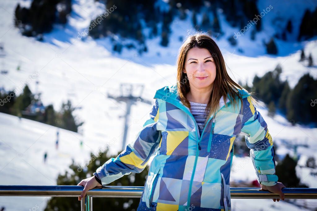 Portrait of smiling Caucasian white woman, skier with ski slopes and ski lifts in background. Winter holidays in El Tarter, Grandvalira, Andorra