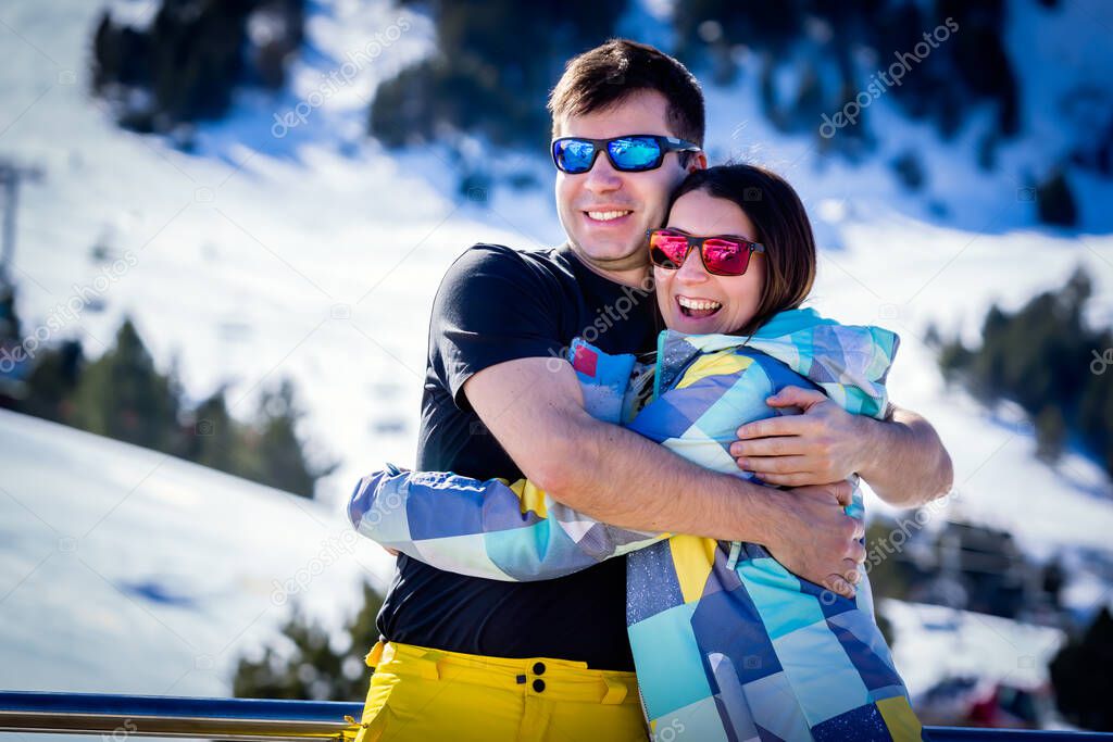 Couple, male and female, of skiers hugging and enjoying their winter holidays with winter background. El Tarter, Grandvalira, Andorra