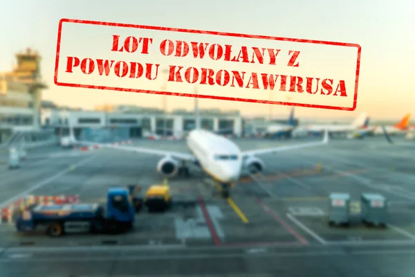 Defocused view of grounded passenger airplanes on empty and closed airport due to coronavirus with Polish notice Flight Cancelled due to Coronavirus