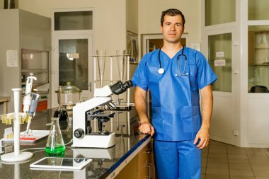 Erkek doktor ya da laboratuvar teknisyeni Coronavirus aşısının bulunmasına yardımcı olmak için mikroskop altında covid 19 virüs numunesini kontrol ediyor ya da araştırıyor