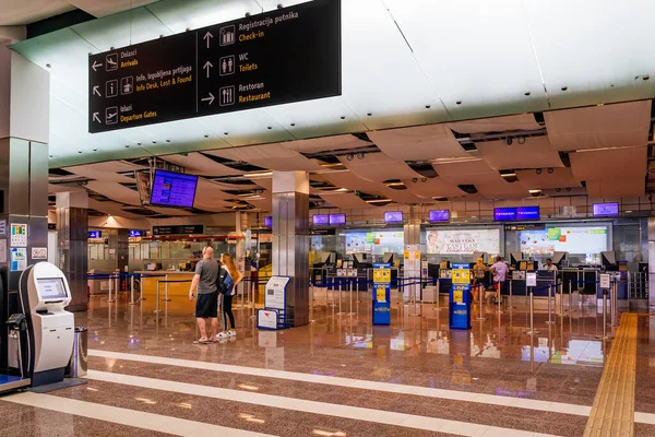 Turistas que se registran para sus vuelos en la sala de salidas en el aeropuerto internacional —  Fotos de Stock