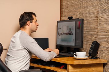 Orta yaşlı bir adam covid 19 ya da koronavirüs salgınları sırasında evindeki konfordan dolayı grafik tablet ve bilgisayar üzerinde çalışıyor.