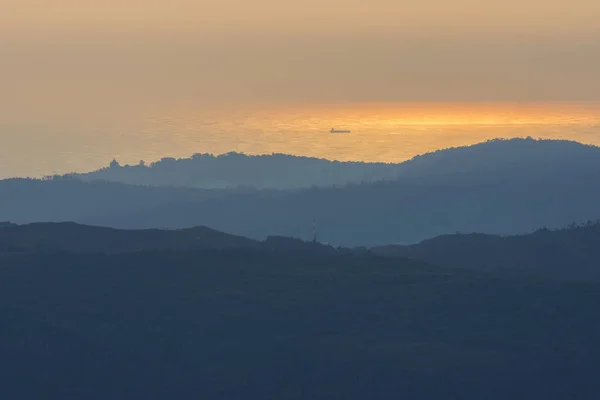 Coucher de soleil au sommet de la montagne avec un navire dans l'océan à l'horizon — Photo