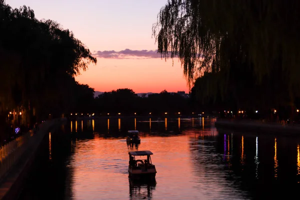Tyst flod vid solnedgången tid med liten båt segling — Stockfoto