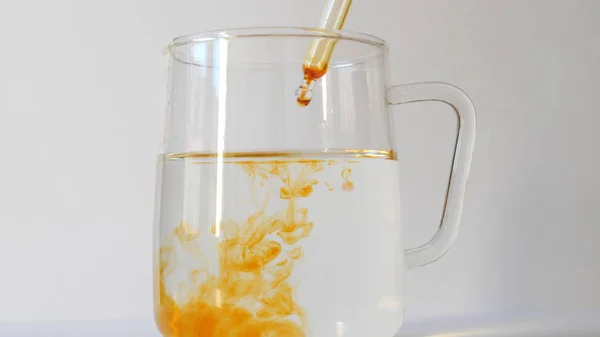 Bir bardak temiz suya iyot damlatıyor. Lugol 'un çözümü.