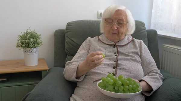 Yaşlı kadın yeşil üzüm yiyor.. — Stok fotoğraf