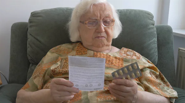 Старшая женщина читает брошюру о лекарствах — стоковое фото