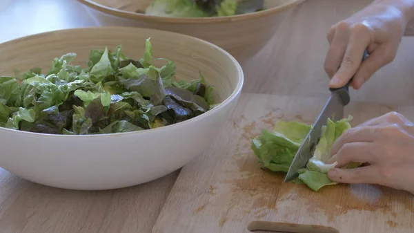Kadın salata için kesme tahtasında marul yaprakları kesiyor — Stok fotoğraf