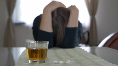 Sarhoş ya da hasta kadın. Acohol ve uyuşturucu kullanımı. Kadın deodaklanmış. Bir bardağa odaklanın.