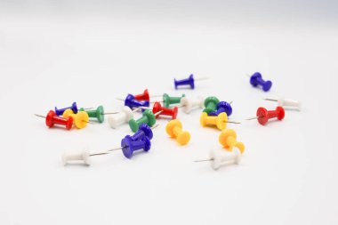 Beyaz kağıt ve defter üzerinde renkli raptiyeler