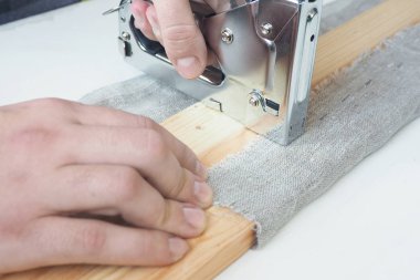 Erkeklerin elleri inşaat zımbasıyla kaba tahtaya sarılmış.