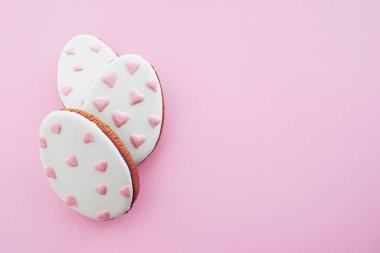 Pembe arka planda pembe kalpleri olan üç yumurta şeklinde zencefilli kurabiye. Paskalya konsepti