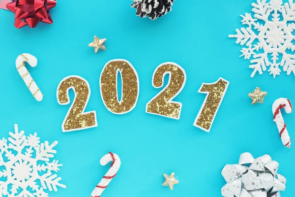 2021 numara, mavi arka planda beyaz kenarlı, altın gibi parlak sayılar. İki tane dekoratif karamel baston. Düz düzen, üst görünüm