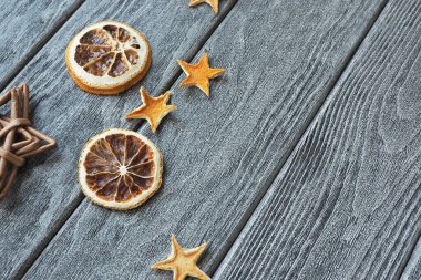 Portakal kabuğundan ve kuru portakal dilimlerinden yapılmış kuru yıldızlar ve ahşap gri arka planda hasır yıldız.