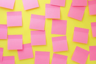 Parlak sarı arka planda bir sürü kare pembe çıkartma var. Notlar için tahta