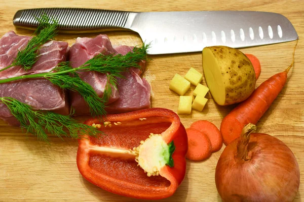 Tábua de corte de madeira com carne, legumes e ervas. faca cozida para cozinhar — Fotografia de Stock