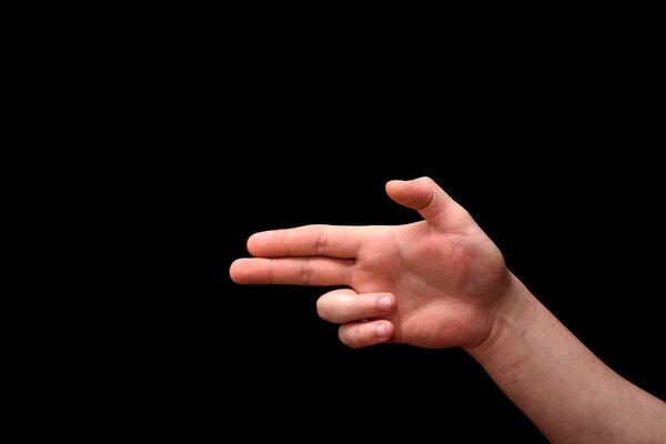 Pistol icon formed from fingers on a black background. isolated photo
