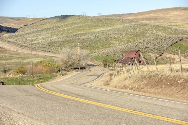 Draaiende weg leidt langs een oude schuur — Stockfoto