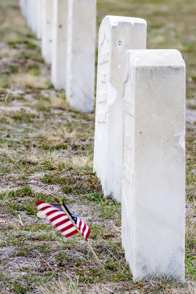 Mini American flagg faps in the wind near a grave