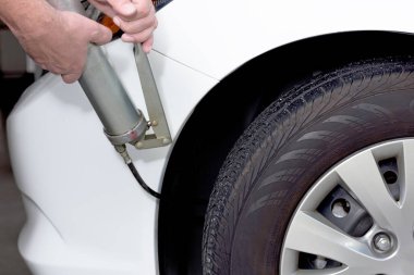 Bir arabayı yağlamak için yağ tabancası kullanmak.