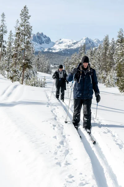 Esquiadores siguen un sendero de fondo en la nieve con una montaña — Foto de Stock