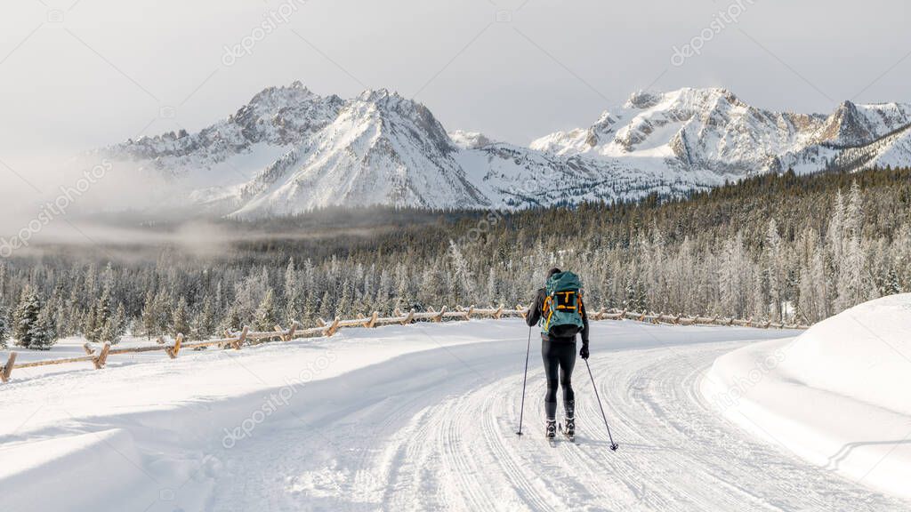 Cross country skiing man travels along a trail to a mountain range