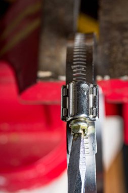 Metal hortum kıskacında düz bıçaklı tornavida.