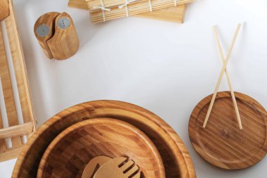 Arka planda beyaz bir masa üzerinde bambu mutfak malzemeleri, kâse üst görünüm yapışır