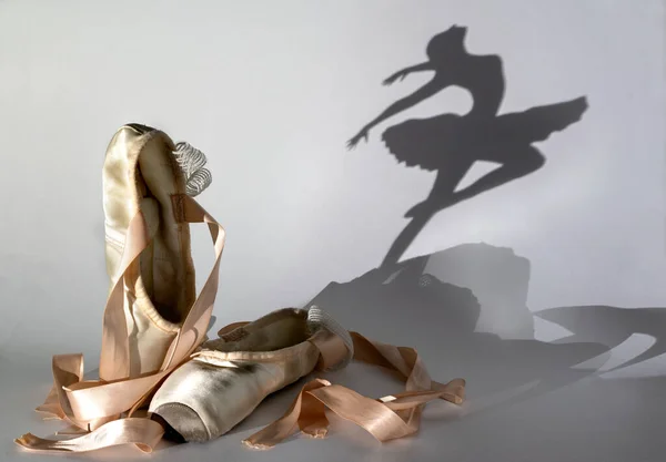 Old pointe shoes with a shadow of dancing ballerina