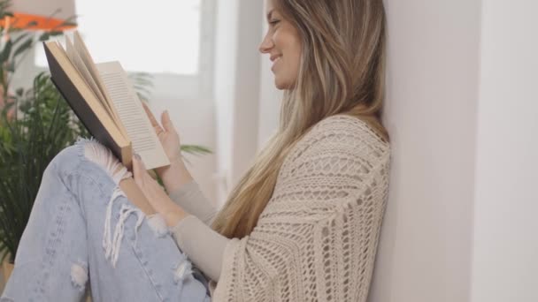 Schöne junge Frau liest ein Buch und lächelt. — Stockvideo