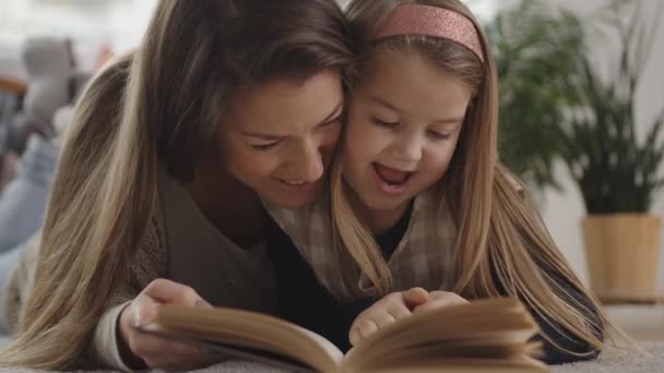 Familia joven leyendo un libro en el suelo de la alfombra — Vídeo de stock