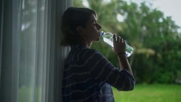 Beautiful caucasian woman drinking bottled water at her porch with a beautiful vivid nature view. Slow motion. — Stock Footage Beautiful caucasian woman drinking bottled water at her porch with a beautiful vivid nature view. Slow motion. Stock Footage