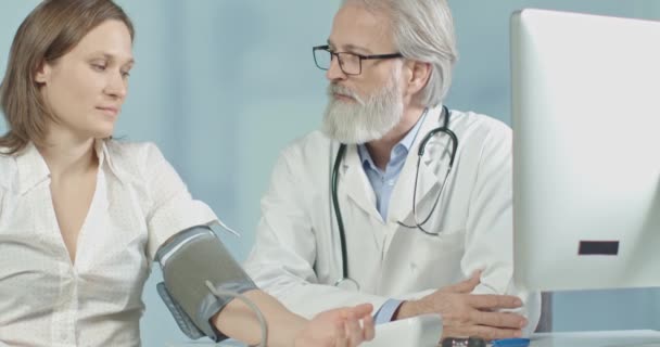 Medico nel suo ufficio che misura la pressione sanguigna della sua paziente femminile — Video Stock