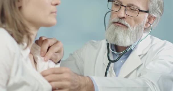 Inyección media de un médico en su consultorio midiendo el pulso de su paciente femenino con su estetoscopio de fantasía. — Vídeo de stock
