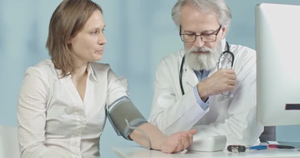Médico en su consultorio midiendo la presión arterial de su paciente femenino — Vídeos de Stock