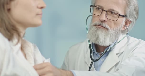Läkare på jobbet, mäter pulsen på sin kvinnliga patient med sitt tjusiga stetoskop.4k slow motion — Stockvideo