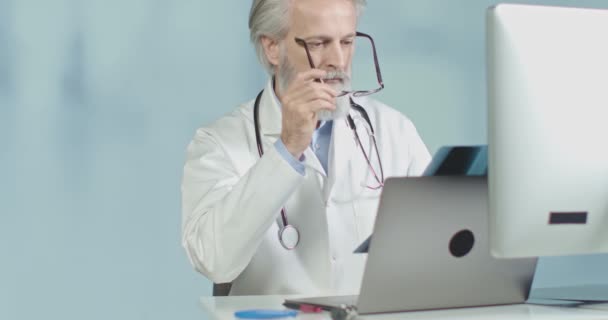 Медичний лікар у своєму кабінеті дивиться на рентгенівські та кшталт сканування. Середній постріл, повільний рух 4k . — стокове відео