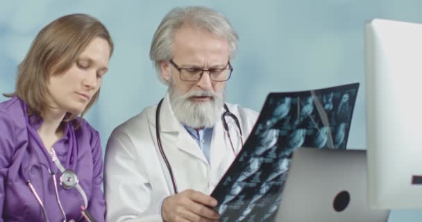 Medical doctor and a nurse looking at x-ray and ct scans of corona virus infected patient at the hospital. Medium shot, 4k slow motion. — Stock Video