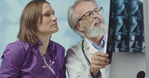 Врач и медсестра смотрят на рентген и КТ. Корона-инфекция. Medium shot, 4k slow motion . — стоковое видео