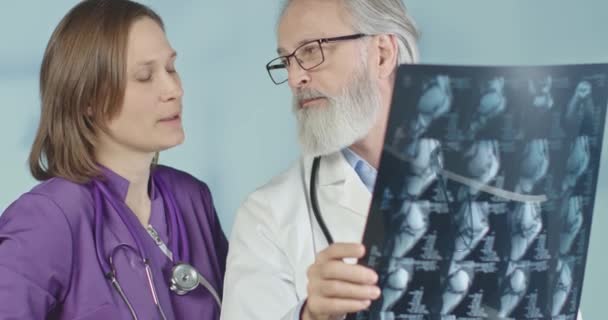 Médico y una enfermera mirando rayos X y tomografías computarizadas en el hospital. Tiro medio, 4k en cámara lenta . — Vídeo de stock